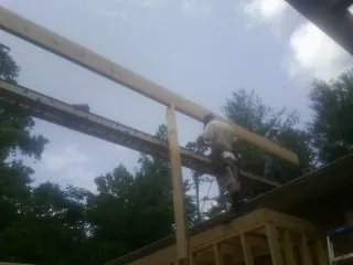 Carpenter setting a ridge beam over a new addition frame — Ice Dam Removal by Roofing Brothers in League City