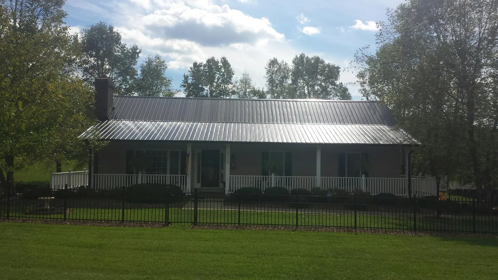 Gray metal roof on a brick ranch with a full width front porch — Gutter Guard Installation work by our crew in League City