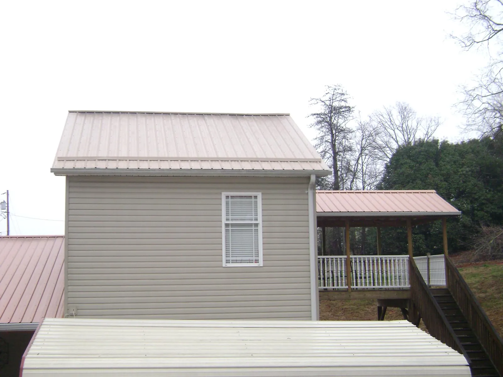 Tan metal roofs on a two story addition and attached porch, from a Roof Replacement job in League City