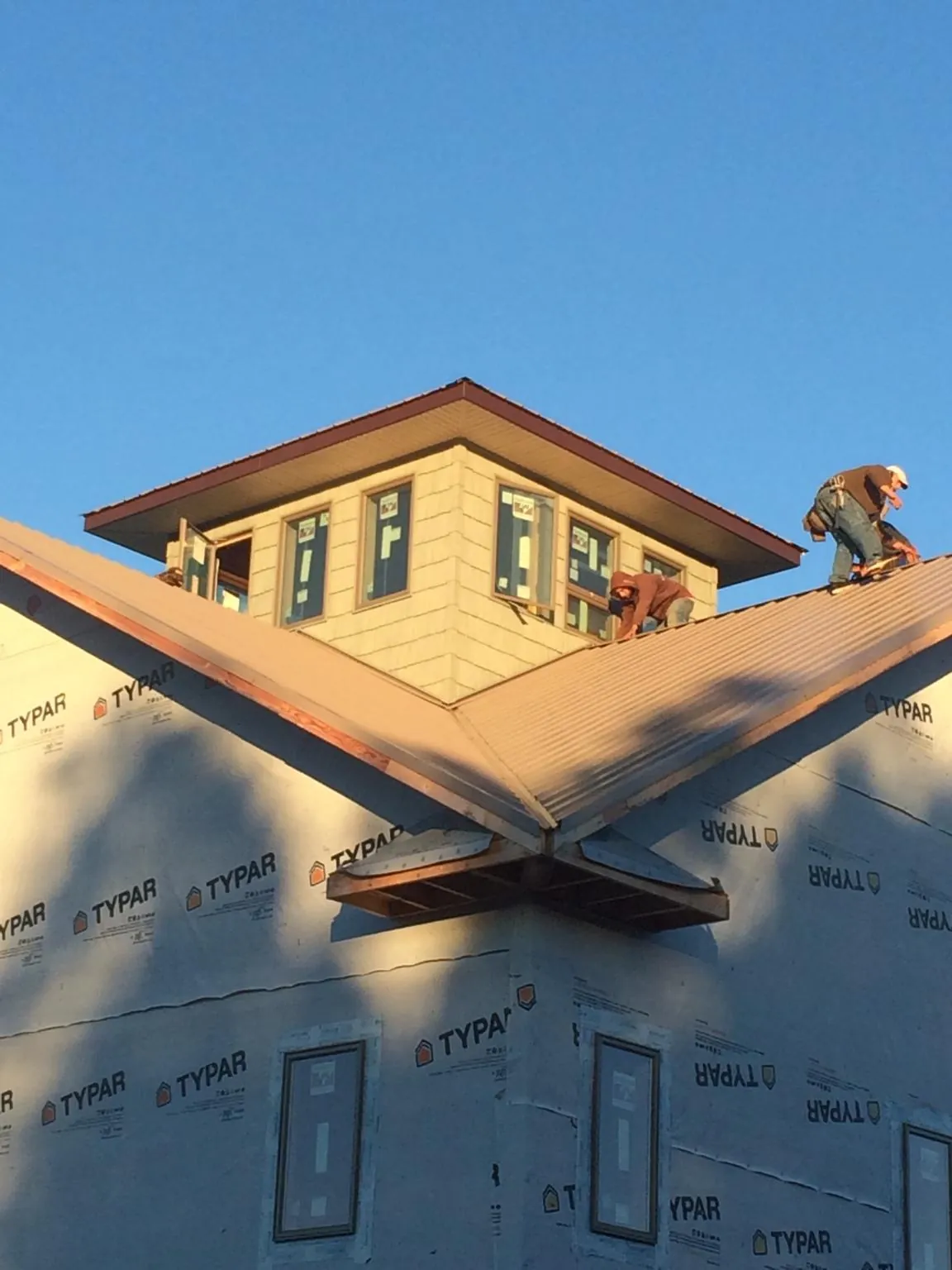 Roofers working around a rooftop cupola on a new metal roof at sunset — Roof Waterproofing in League City by Roofing Brothers